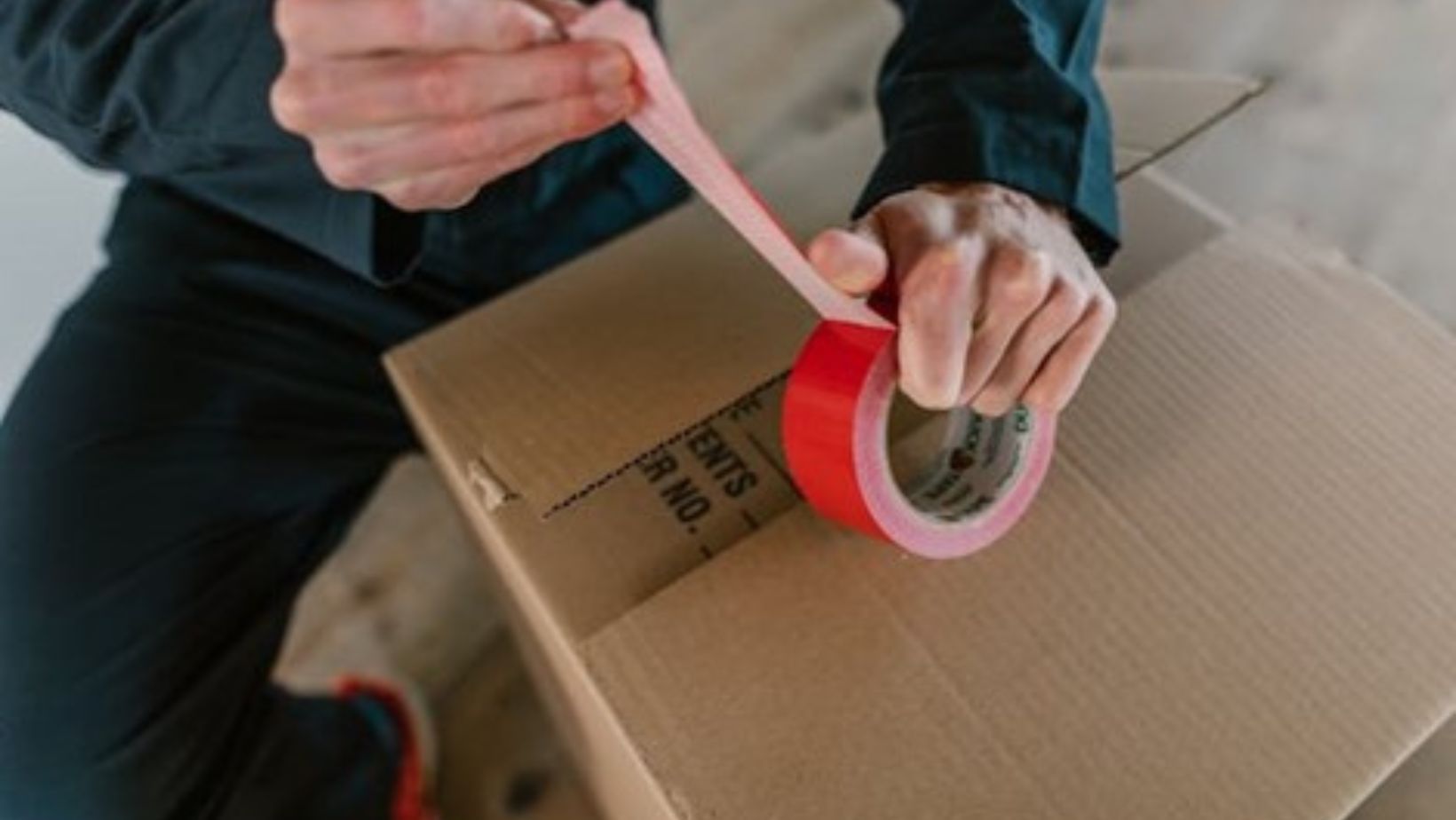 A person holding a red packing tape