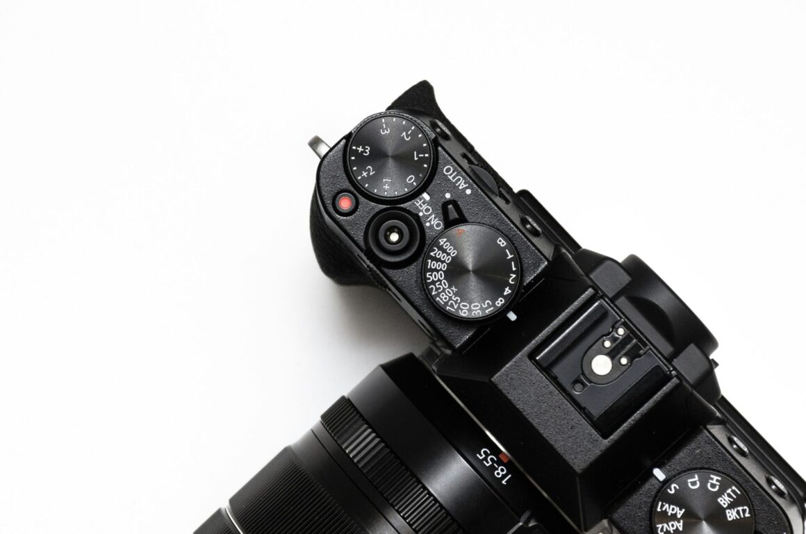 A Black DSLR camera on a white surface, seen from above.