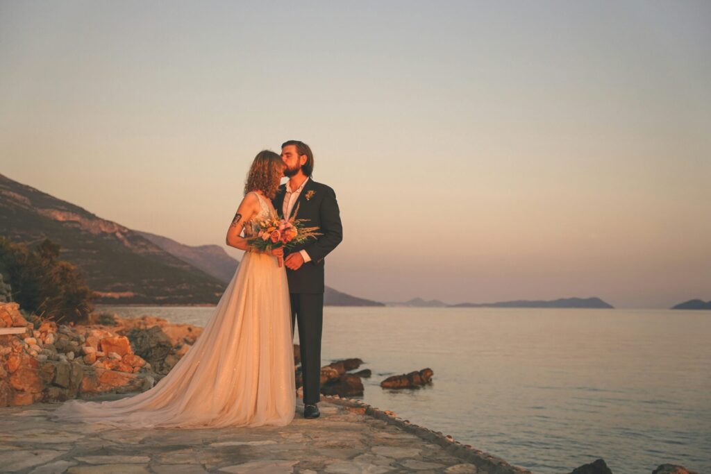 A wedding photo of a couple near the shoreline, at dusk.